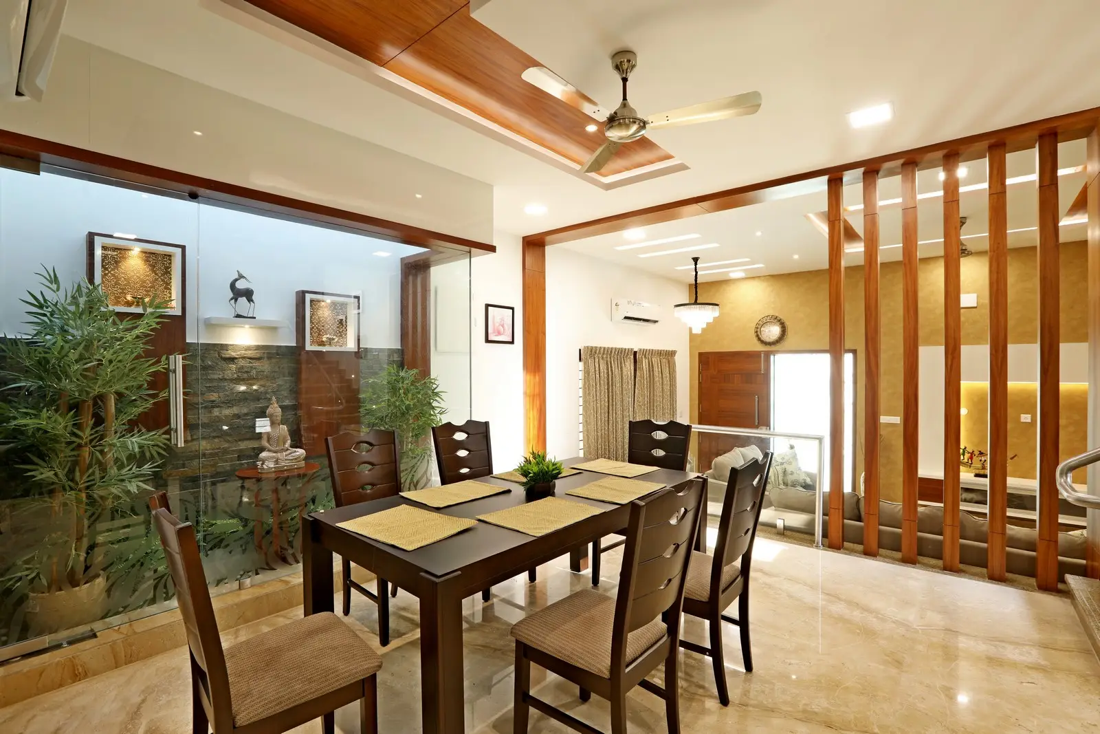 This elegant dining area features a wooden table, warm lighting, marble flooring, and decorative wall panels, creating a refined and inviting atmosphere.
