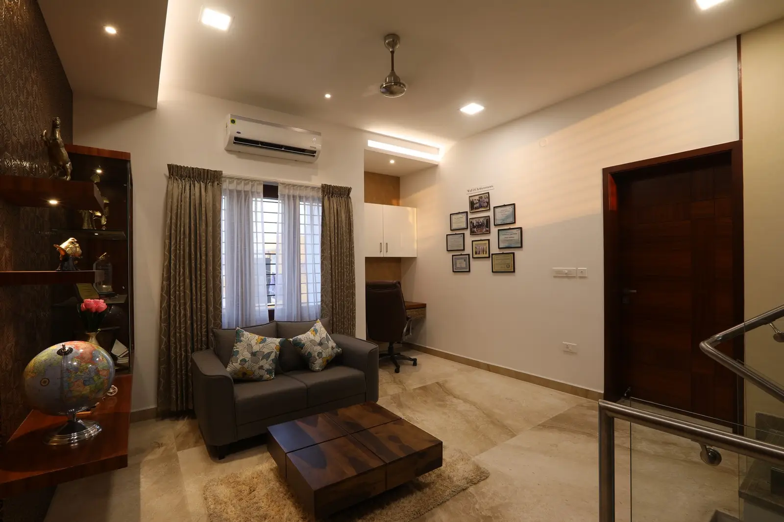 The second floor - features a compact gray sofa, a wooden coffee table, elegant shelving, warm lighting, and a small study nook, creating a refined contemporary ambiance.