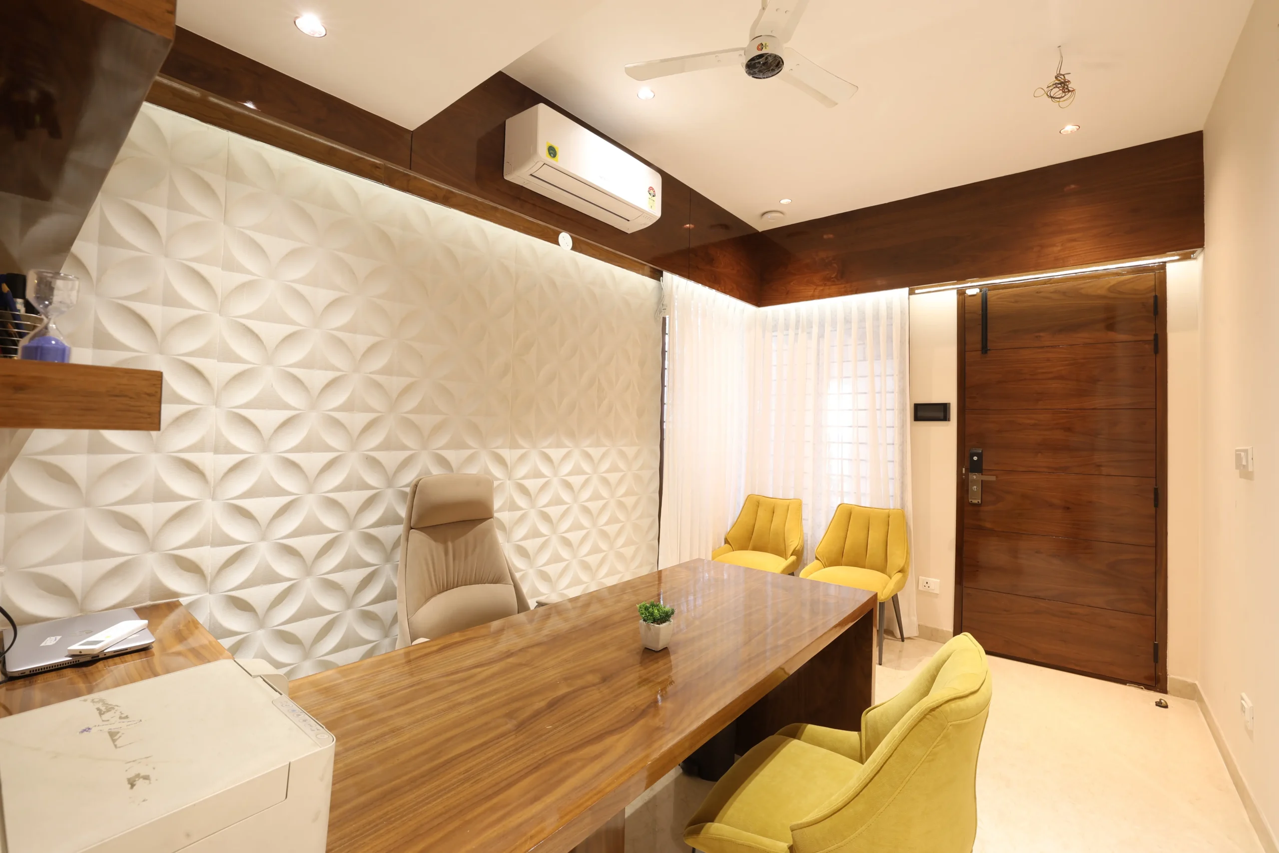 Textured 3D geometric wall in off-white tones, wooden-framed air-conditioning unit, recessed lighting, and light flooring create a balanced, functional, and visually appealing interior.