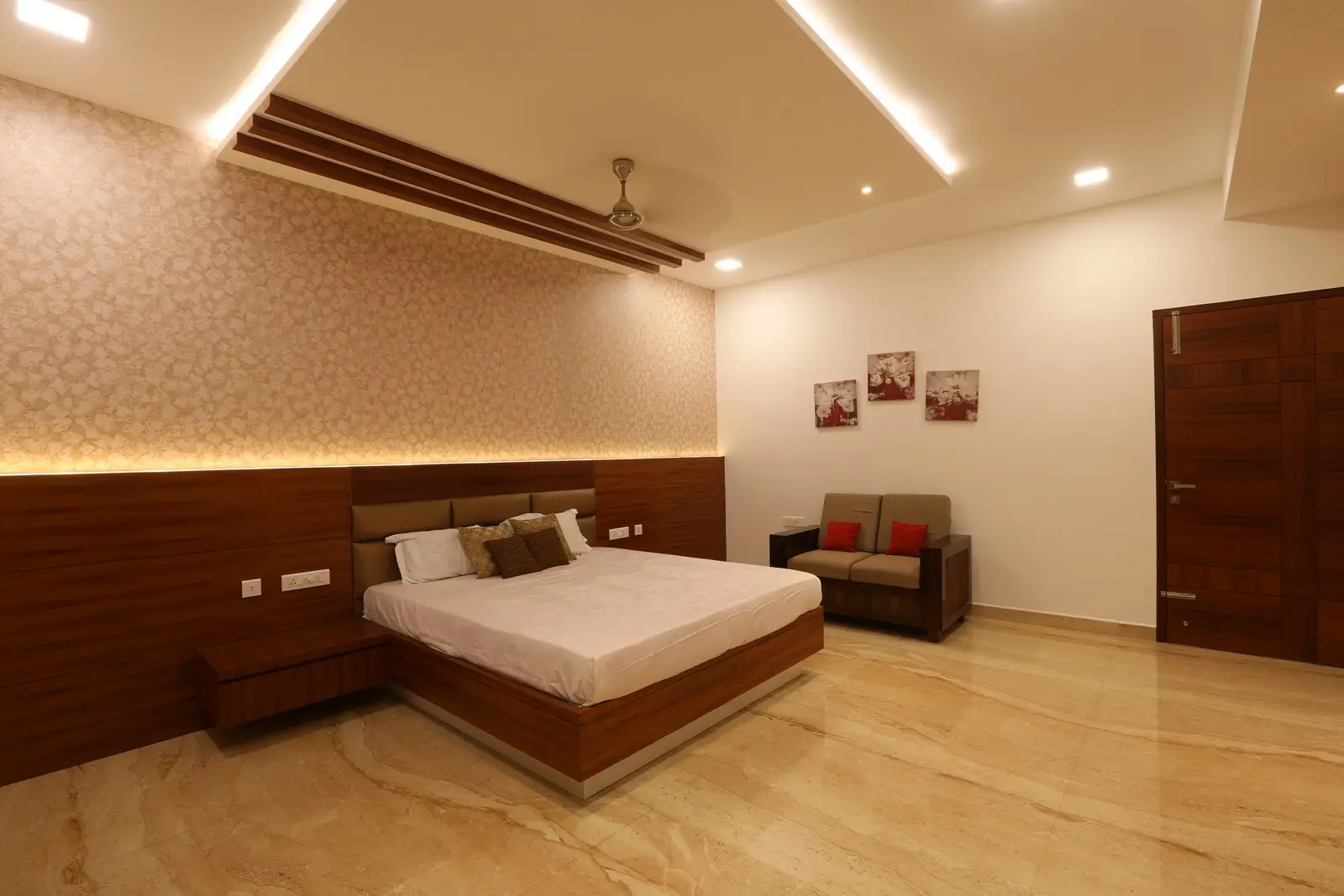 Each bedroom showcases a refined contemporary design featuring marble flooring, sleek wooden furnishings, ambient recessed lighting, and elegant wallpaper, establishing a spacious and welcoming ambiance.

