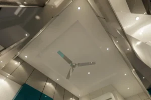 Ceiling view showing a modern white ceiling with recessed lighting and a central ceiling fan with three blades.