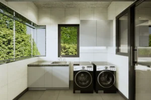 Modern laundry room with two black and white front-loading LG washing machines, a sink with a countertop and cabinet below, white tiled walls, a window with a view of green foliage, and a glass door on the right side.